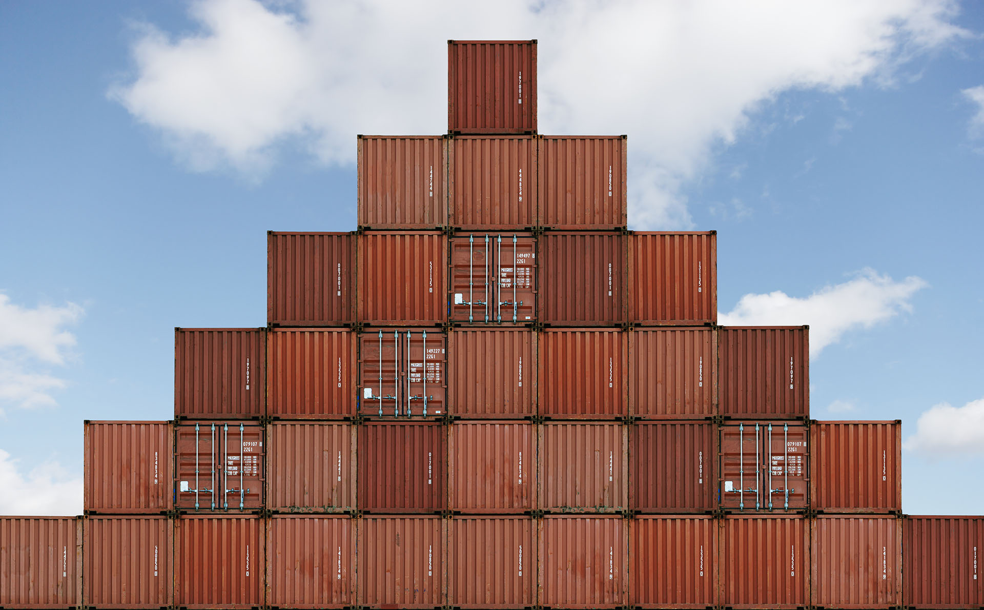 Pyramid of shipping containers, representing the process of scaling enterprise applications with container management techniques