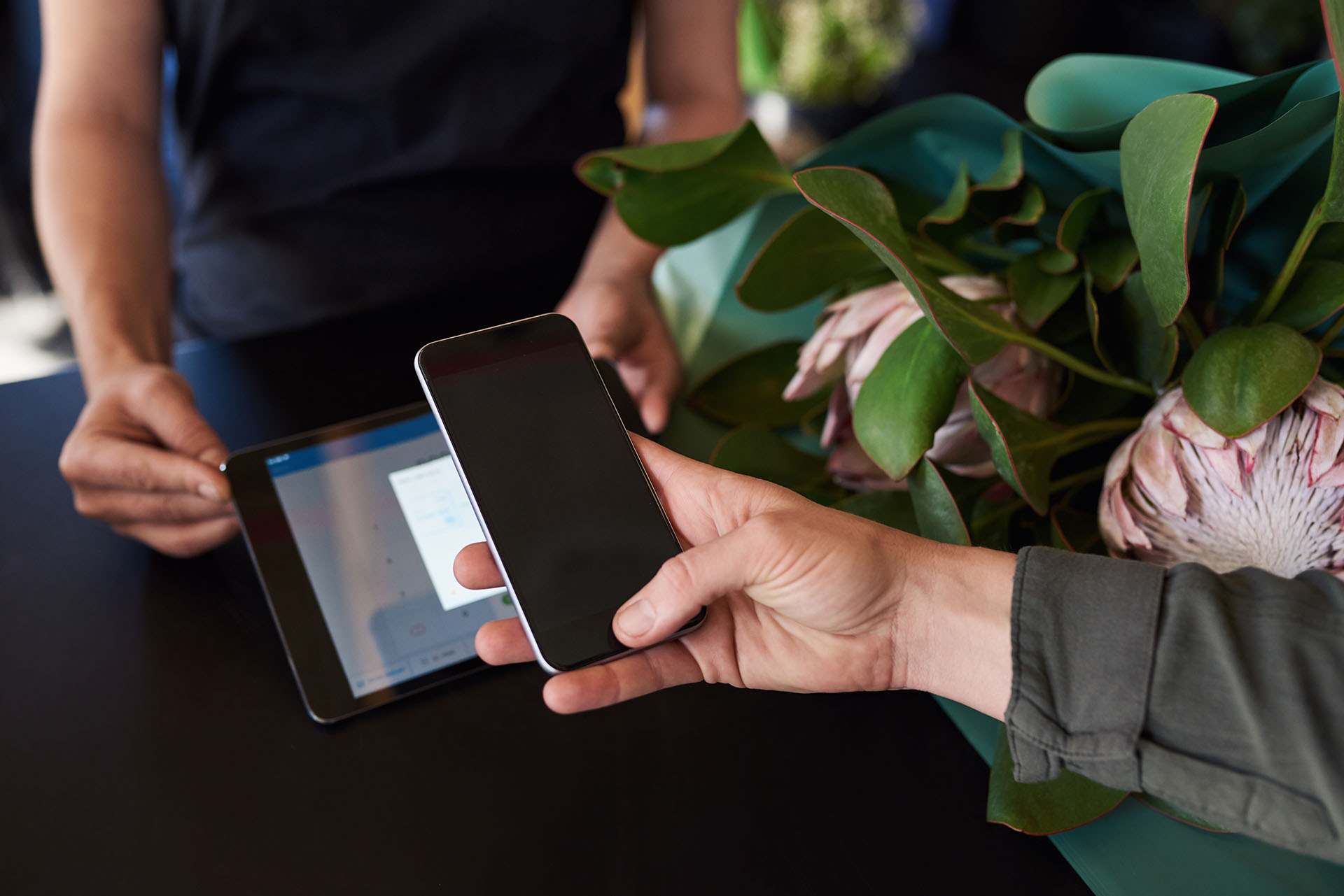 A customer taps their phone to pay on a point-of-sale system, running with edge computing in retail.