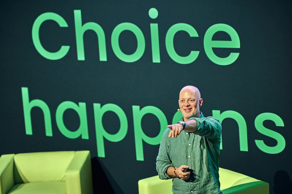 Dr. Thomas di Giacomo, Chief Technology and Product Officer at SUSE, onstage at SUSECON 2024 in front of a screen with the words "Choice Happens"